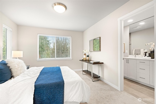 bedroom featuring light carpet, sink, and ensuite bathroom