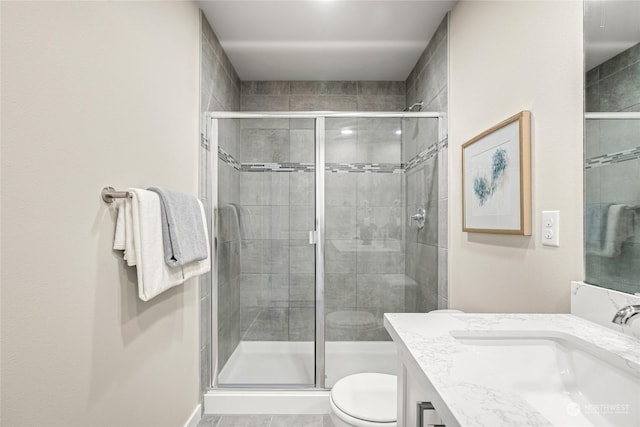 bathroom featuring vanity, toilet, and a shower with door