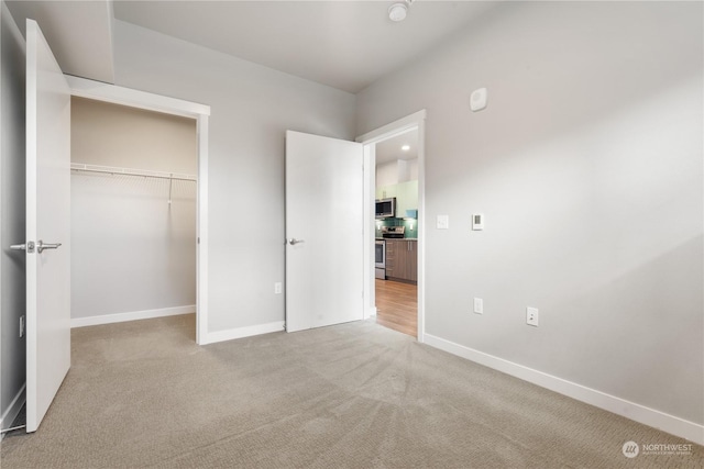 unfurnished bedroom with light colored carpet and a closet