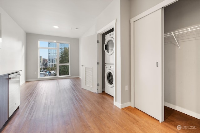 clothes washing area with stacked washer and dryer and light hardwood / wood-style flooring