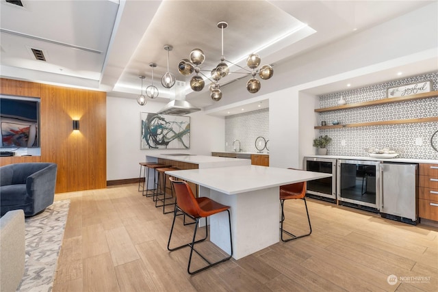 kitchen with a breakfast bar, wine cooler, fridge, a large island, and a tray ceiling