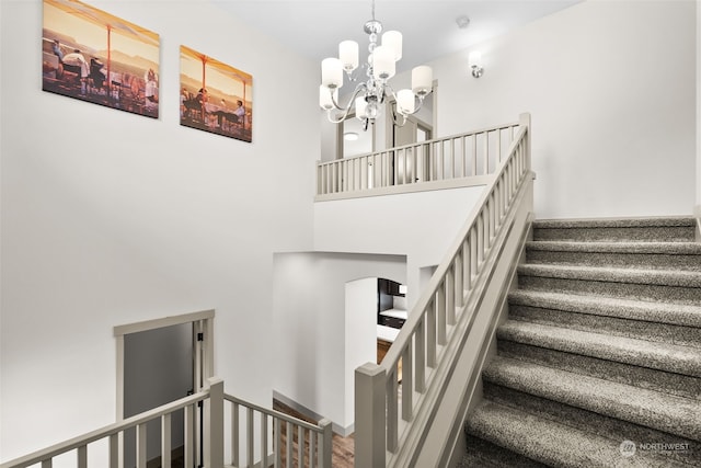 stairway with a towering ceiling and a notable chandelier