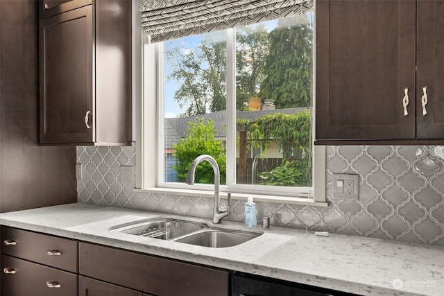 kitchen with tasteful backsplash, sink, dark brown cabinets, and light stone countertops