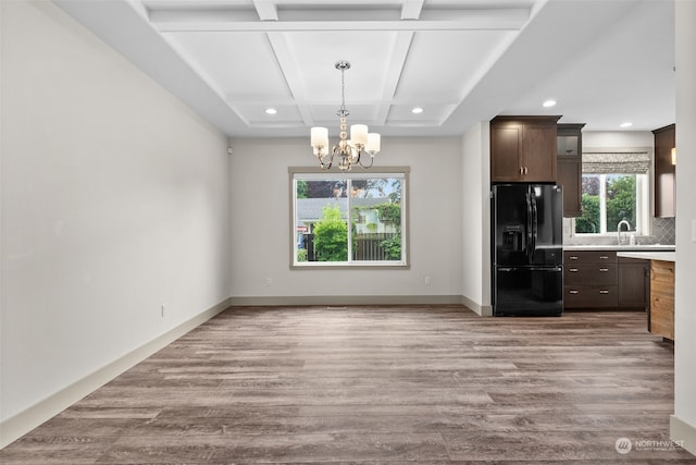 kitchen with tasteful backsplash, black fridge with ice dispenser, coffered ceiling, and light wood-type flooring