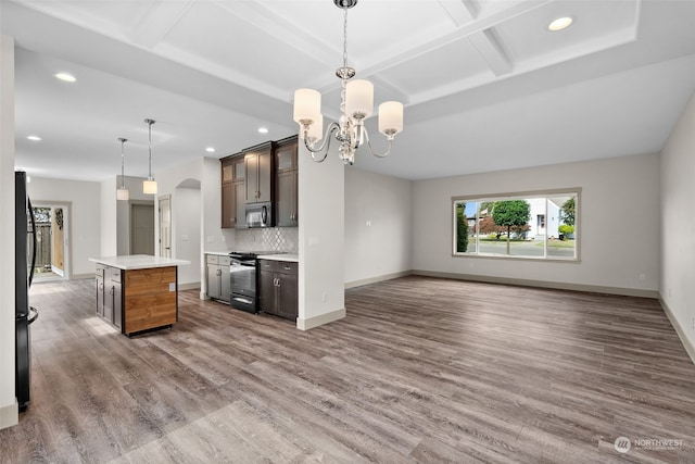 kitchen featuring decorative light fixtures, backsplash, a center island, dark brown cabinetry, and black electric range