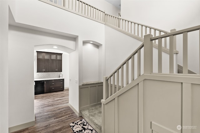 stairs with hardwood / wood-style flooring and a high ceiling