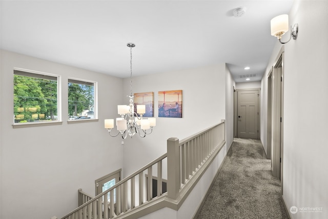 hallway featuring an inviting chandelier and carpet