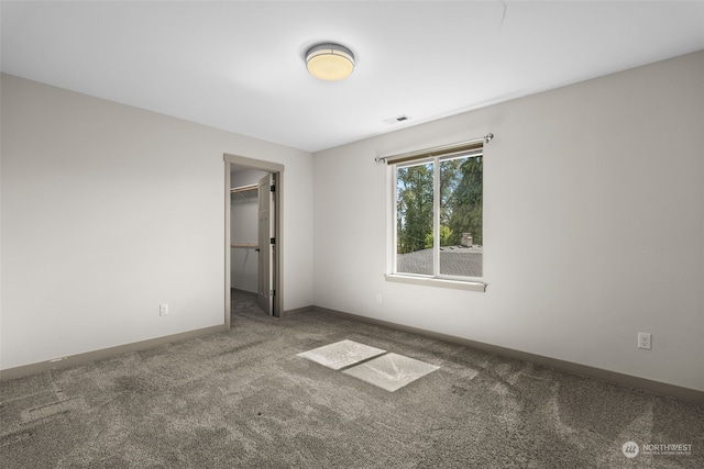 unfurnished bedroom featuring a walk in closet, carpet floors, and a closet