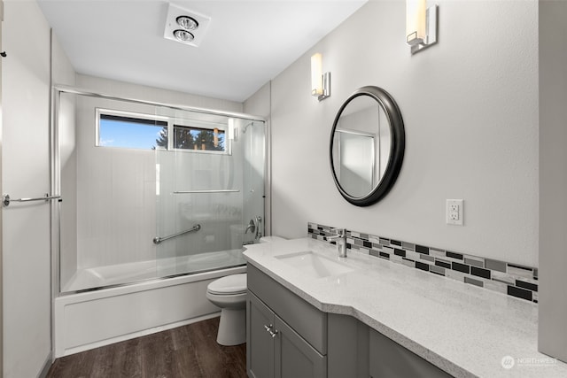 full bathroom with toilet, tasteful backsplash, wood-type flooring, bath / shower combo with glass door, and vanity