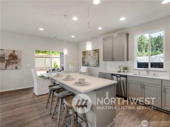 kitchen with sink, gray cabinetry, decorative light fixtures, stainless steel dishwasher, and a kitchen island