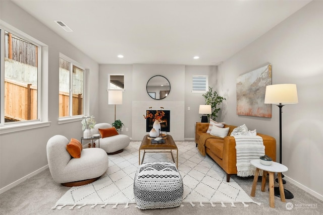 living area featuring light carpet and a fireplace