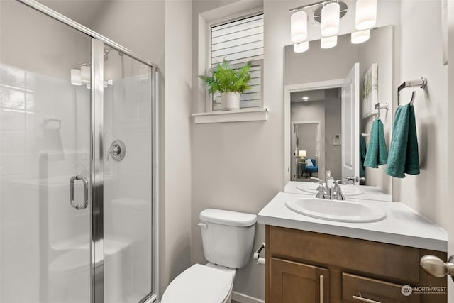 bathroom with a shower with door, vanity, and toilet