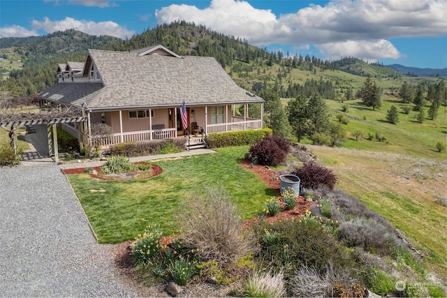 view of front of home featuring a porch, a mountain view, and a front lawn