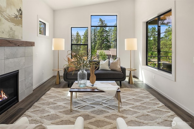 living room featuring lofted ceiling, dark hardwood / wood-style floors, and a tile fireplace