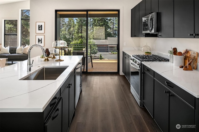 kitchen featuring stainless steel appliances, sink, dark wood-type flooring, and a kitchen island with sink