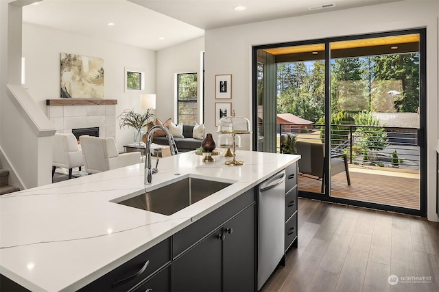 kitchen featuring sink, dark wood-type flooring, dishwasher, a center island, and a fireplace