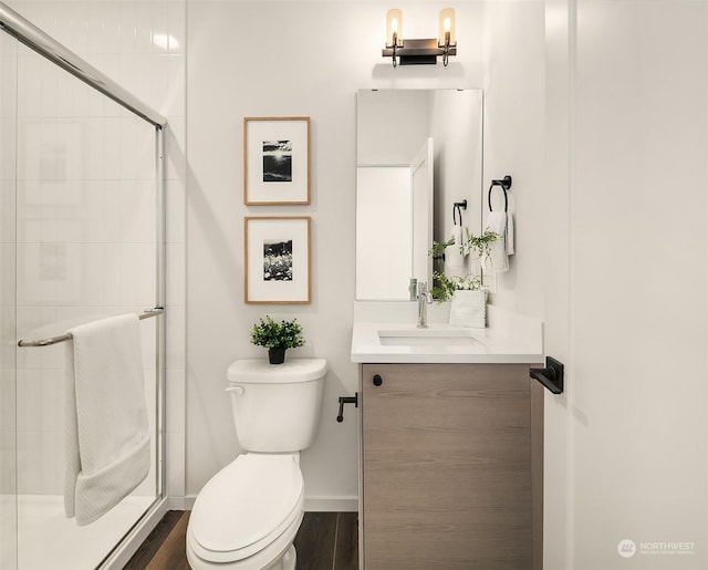 bathroom featuring vanity, hardwood / wood-style flooring, a shower with door, and toilet