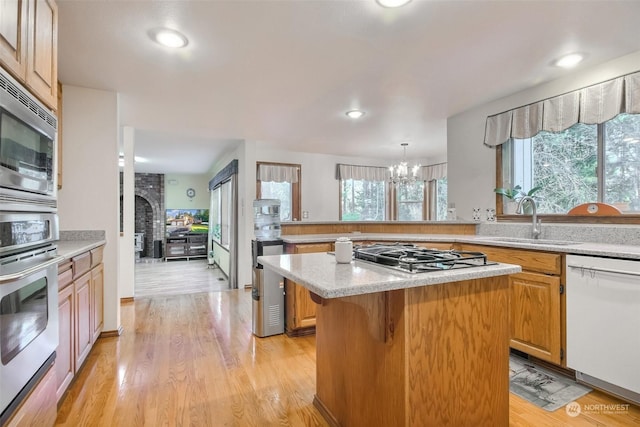 kitchen with sink, a breakfast bar area, appliances with stainless steel finishes, a kitchen island, and decorative light fixtures