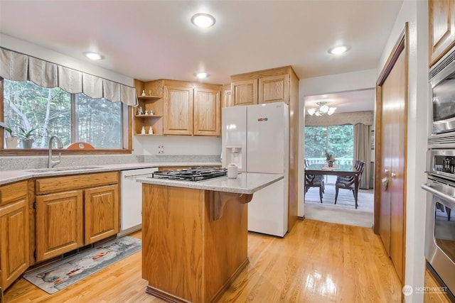 kitchen with a breakfast bar, sink, light hardwood / wood-style flooring, a kitchen island, and stainless steel appliances