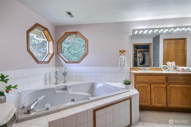 bathroom featuring vanity and a relaxing tiled tub