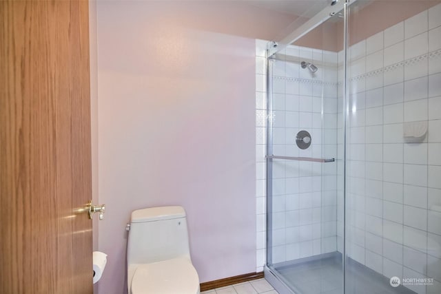 bathroom featuring a shower with shower door and toilet