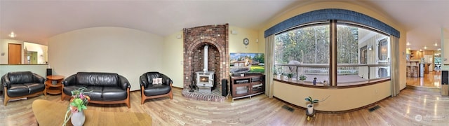 interior space with lofted ceiling, a wood stove, and hardwood / wood-style floors