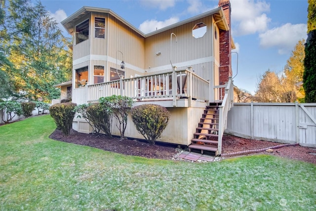 rear view of property featuring a deck and a lawn