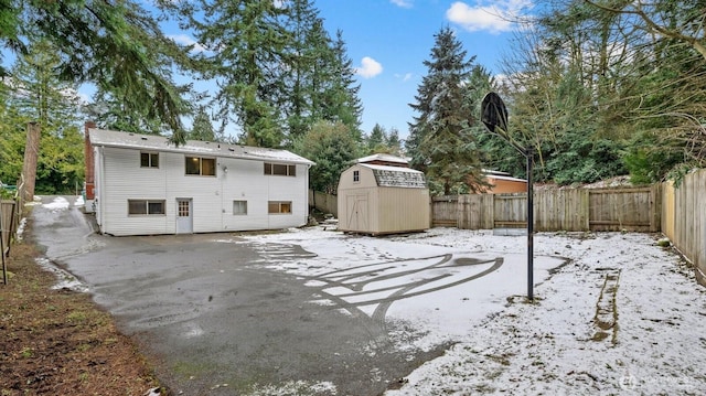 rear view of property with an outdoor structure, a fenced backyard, a shed, and a patio area