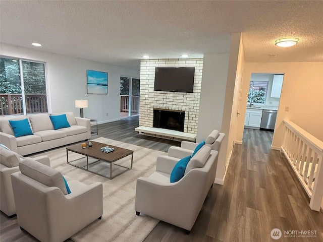 living room featuring a fireplace, recessed lighting, a textured ceiling, wood finished floors, and baseboards