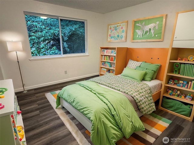 bedroom with a textured ceiling, baseboards, and wood finished floors