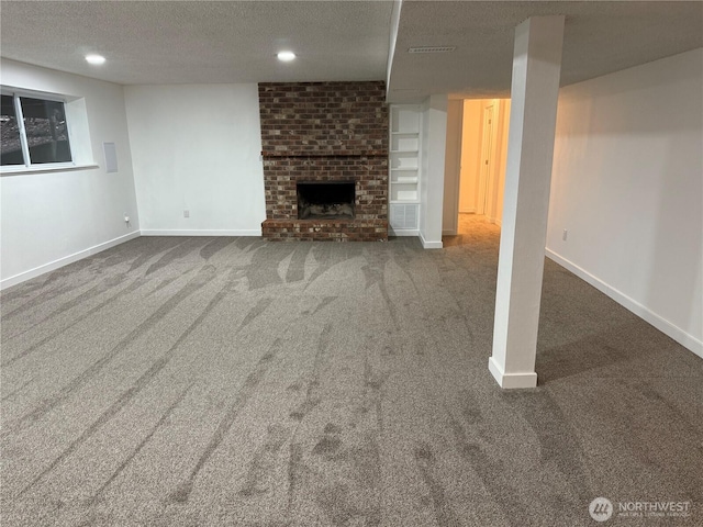 finished basement with a brick fireplace, baseboards, a textured ceiling, and carpet flooring