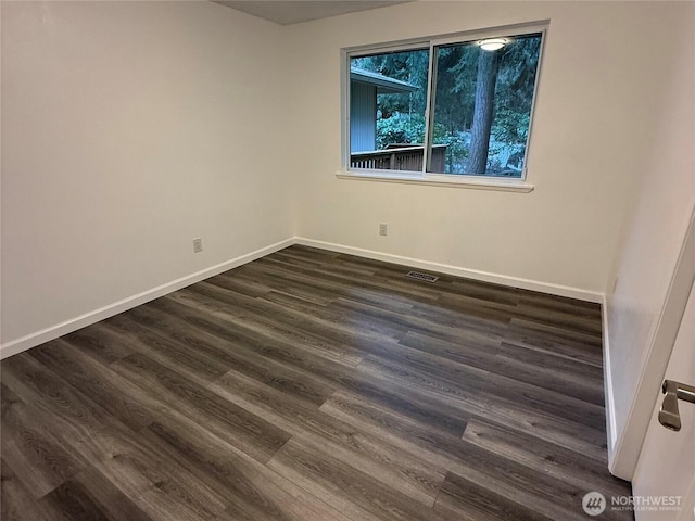 unfurnished room with visible vents, baseboards, and dark wood finished floors