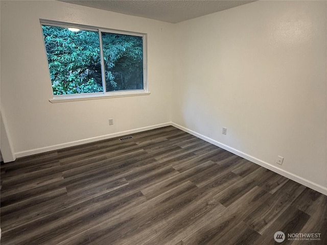 unfurnished room with dark wood-style floors, a textured ceiling, visible vents, and baseboards