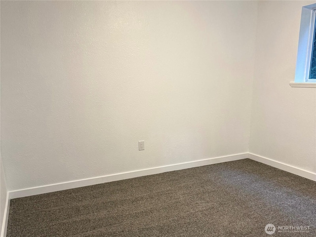 spare room with dark colored carpet and baseboards