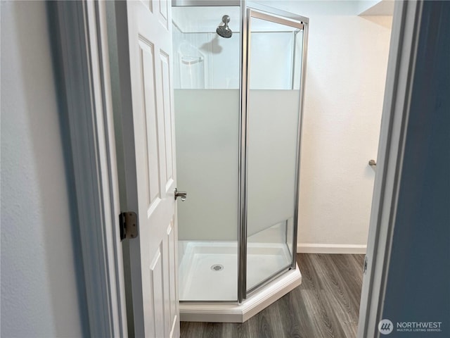 full bathroom with a shower stall, baseboards, and wood finished floors