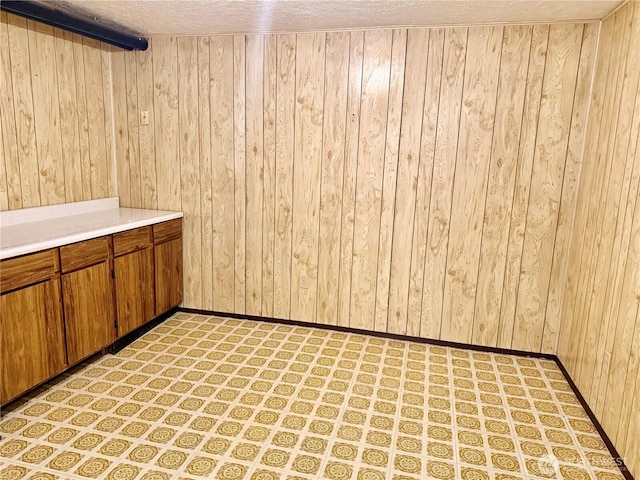 empty room featuring wood walls, baseboards, and a textured ceiling