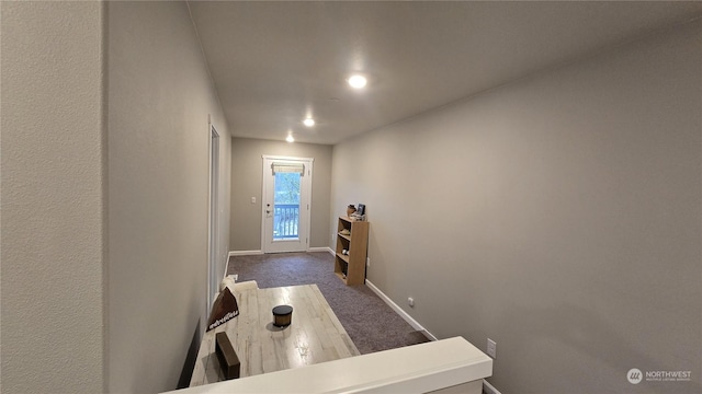 interior space featuring dark colored carpet and baseboards