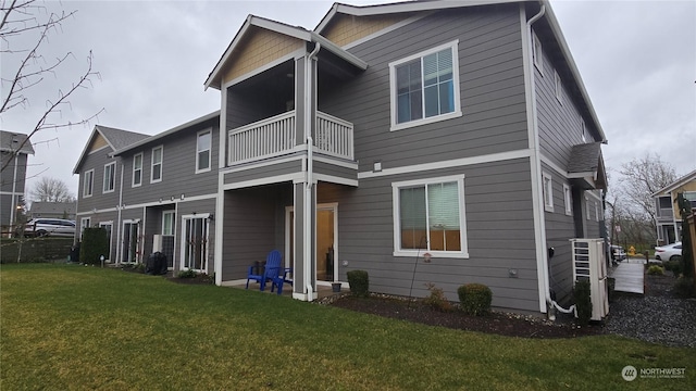 back of property with a yard and a balcony