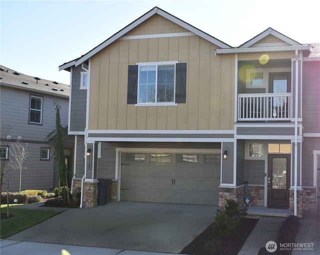 view of front of property featuring stone siding, an attached garage, a balcony, and driveway