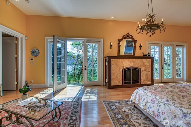bedroom featuring an inviting chandelier, access to outside, french doors, and light wood finished floors