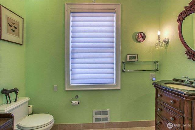 bathroom featuring heating unit, toilet, and vanity