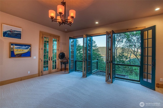 carpeted empty room with recessed lighting, french doors, baseboards, and an inviting chandelier