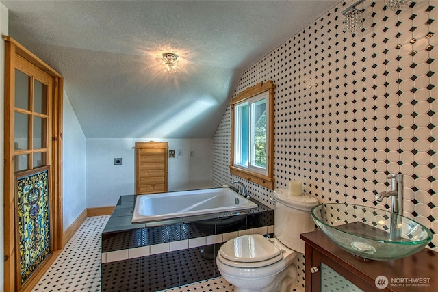 bathroom with toilet, a textured ceiling, baseboards, a bath, and vaulted ceiling