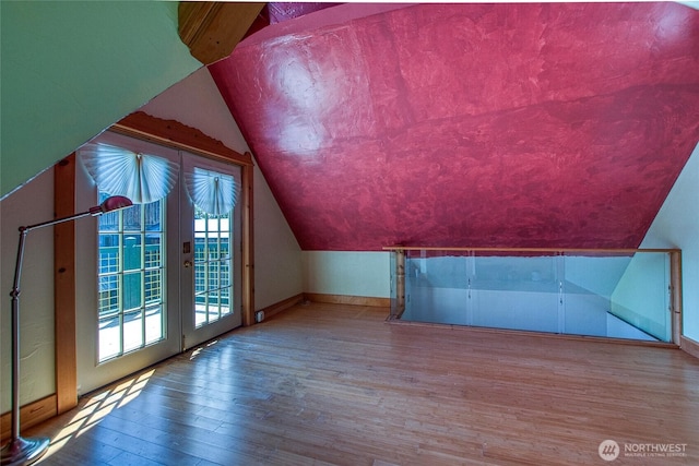 bonus room featuring french doors, baseboards, wood finished floors, and vaulted ceiling