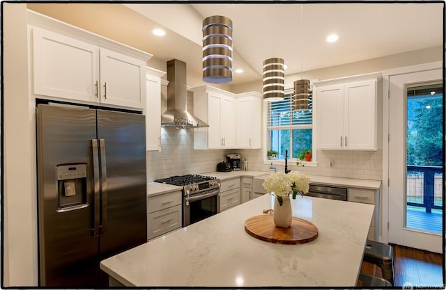 kitchen featuring appliances with stainless steel finishes, pendant lighting, white cabinets, and wall chimney exhaust hood