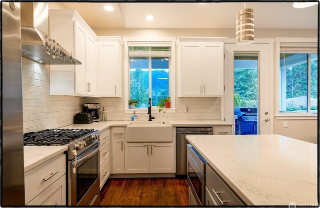 kitchen with wall chimney range hood, stainless steel appliances, and white cabinets