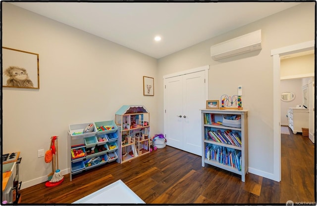 game room featuring a wall mounted air conditioner and dark hardwood / wood-style flooring