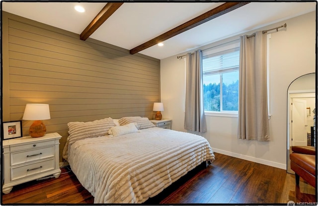 bedroom with beamed ceiling, wooden walls, and dark hardwood / wood-style flooring