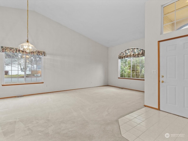 carpeted entrance foyer with high vaulted ceiling and a chandelier