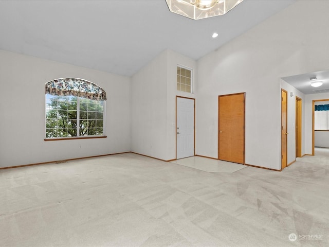 empty room featuring a towering ceiling and light carpet